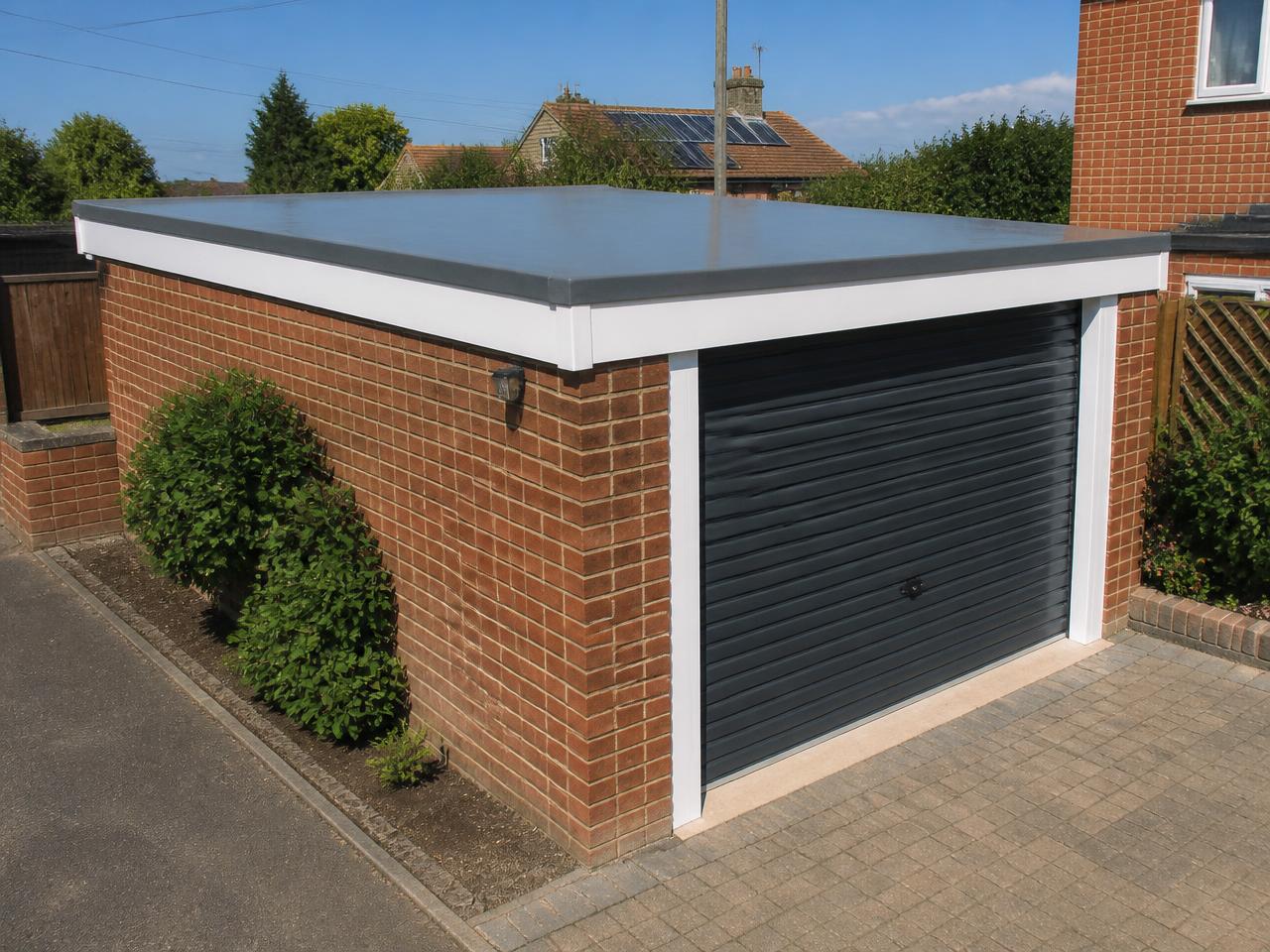 A brick garage with a new grey fibreglass flat roof and white edge trims